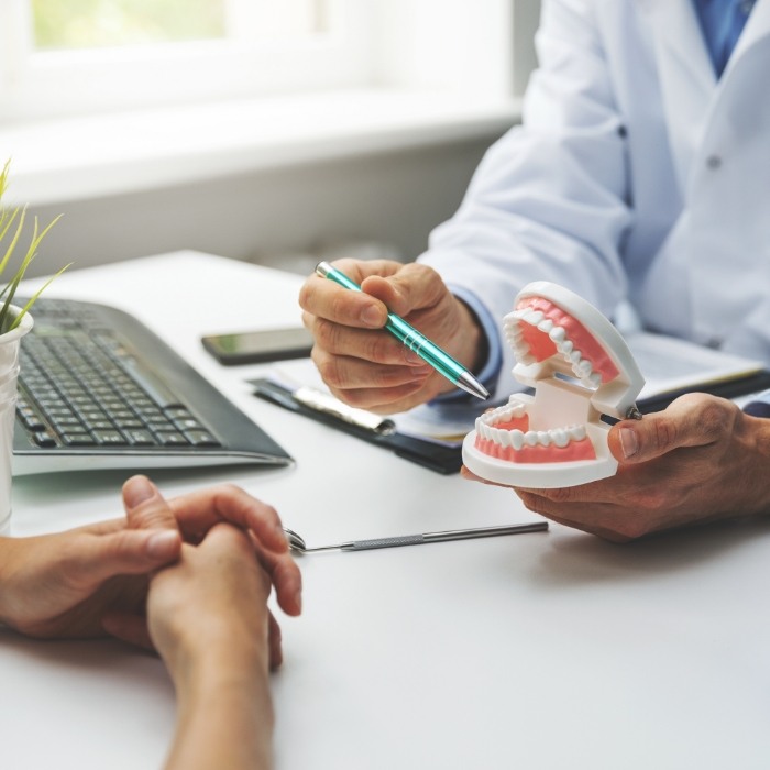 Dentist showing a denture model to a patient