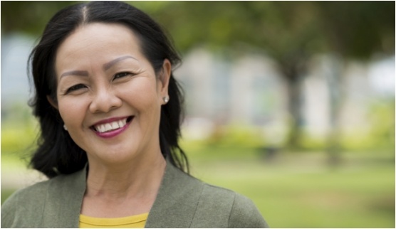 Woman in dark green blazer grinning outdoors