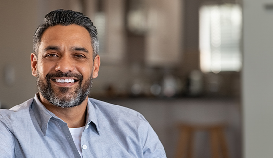 Man in pale blue button up shirt smiling