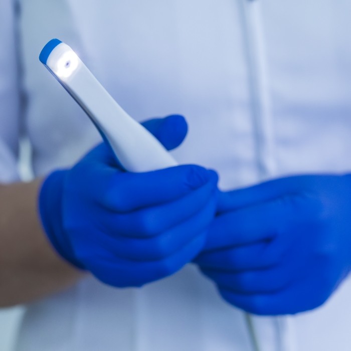 Dental team member holding thin white intraoral camera