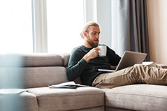 a man relaxing on a couch with his laptop