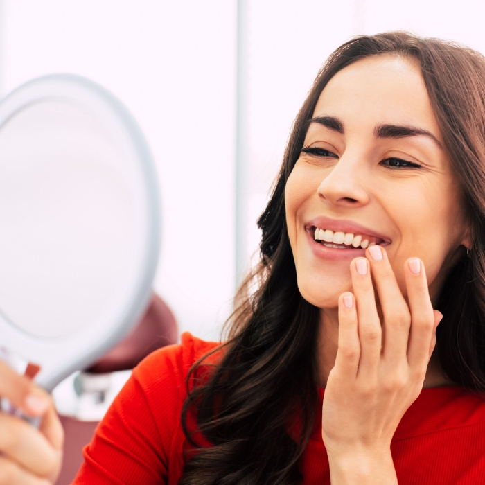 Dental patient admiring her smile in a mirror