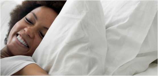 Smiling woman stretching while laying in bed