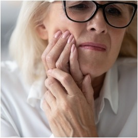 Woman wincing and holding her cheek in pain