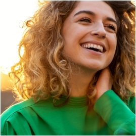 Young woman with curly hair smiling outdoors