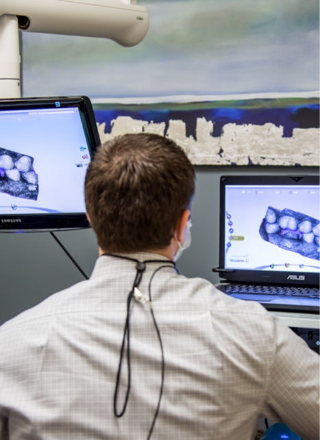 Dentist looking at computer screens showing digital models of teeth