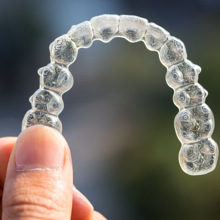 Hand holding an Invisalign clear aligner in Plattsburgh
