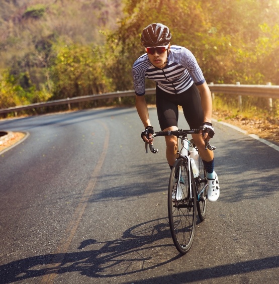 Man riding bike on road with forest in background