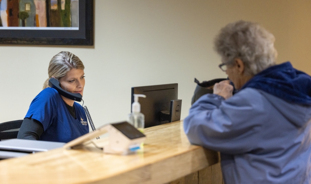 Dental team member answering phone at front desk of Plattsburgh dental office