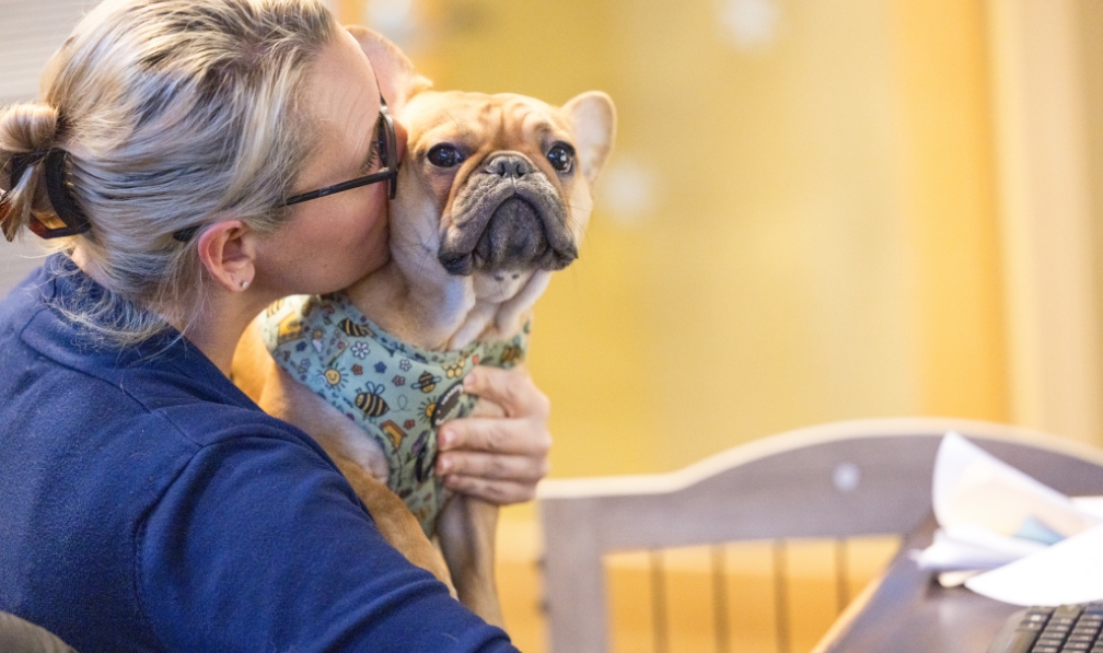 Dental team member kissing Ruby the dental office therapy dog