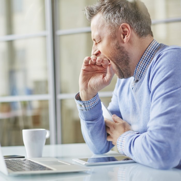 Man yawning while sitting at desk with computer